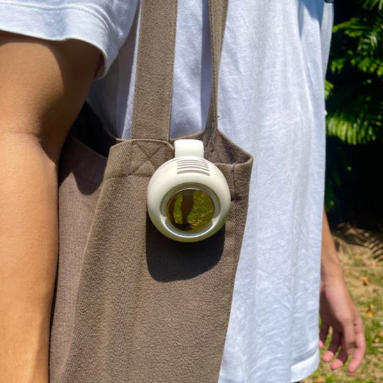 A portable clip fan attached to the side of a tote bag