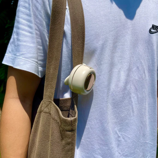 A portable clip fan attached to the strap of a tote bag